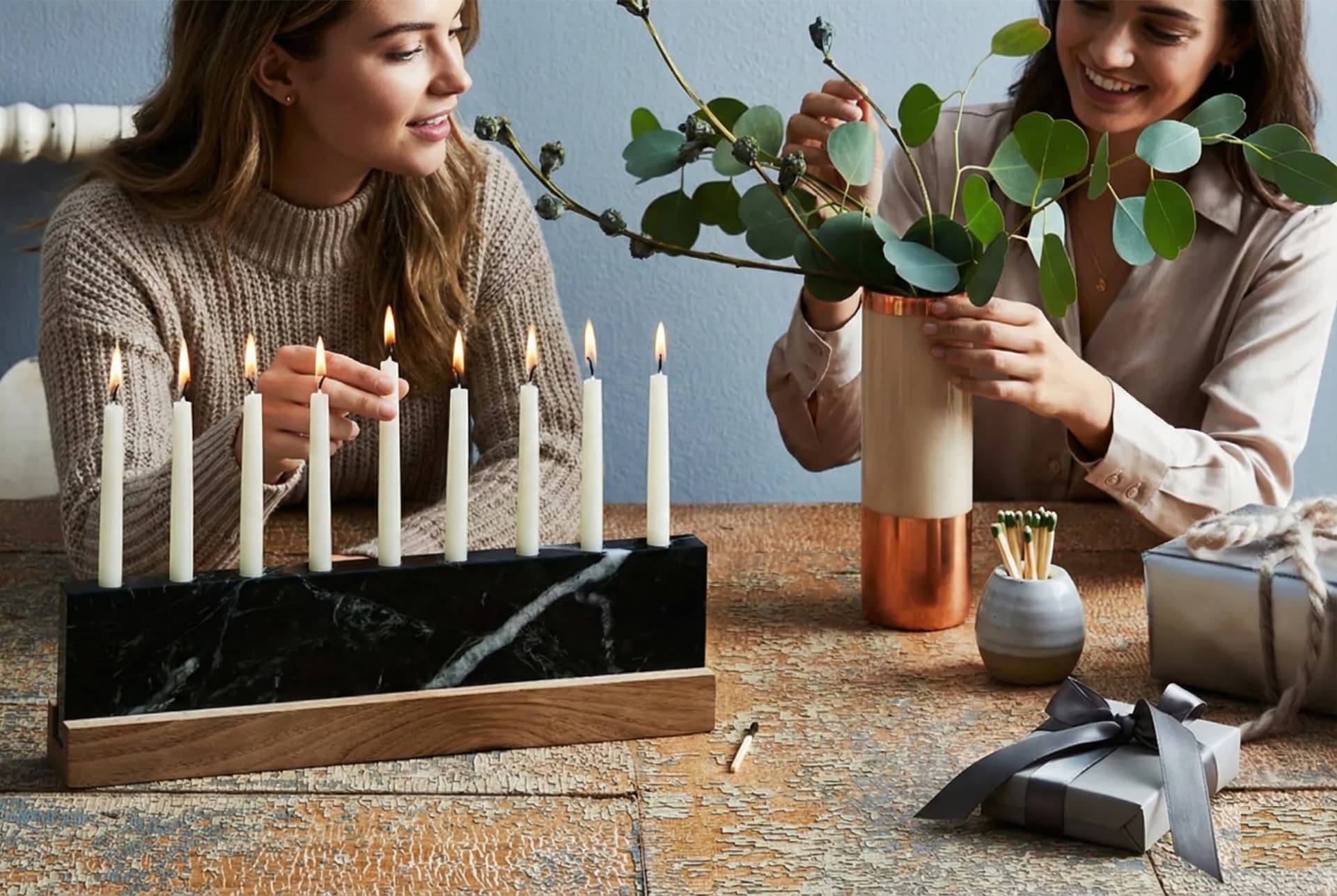 Modern menorah display mixing brass, glass, and sculptural ceramic pieces on a holiday table